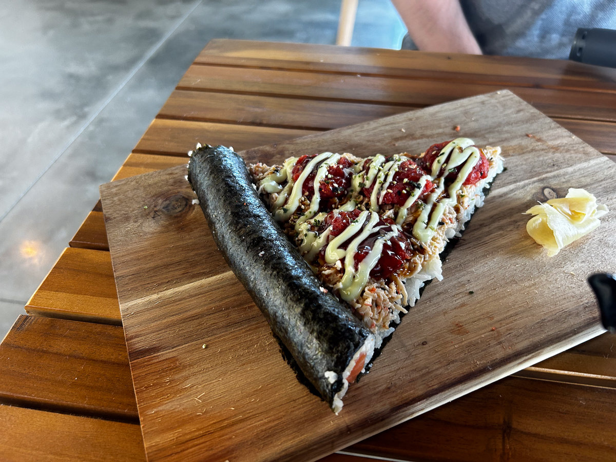 slice of sushi pizza on a wooden plate